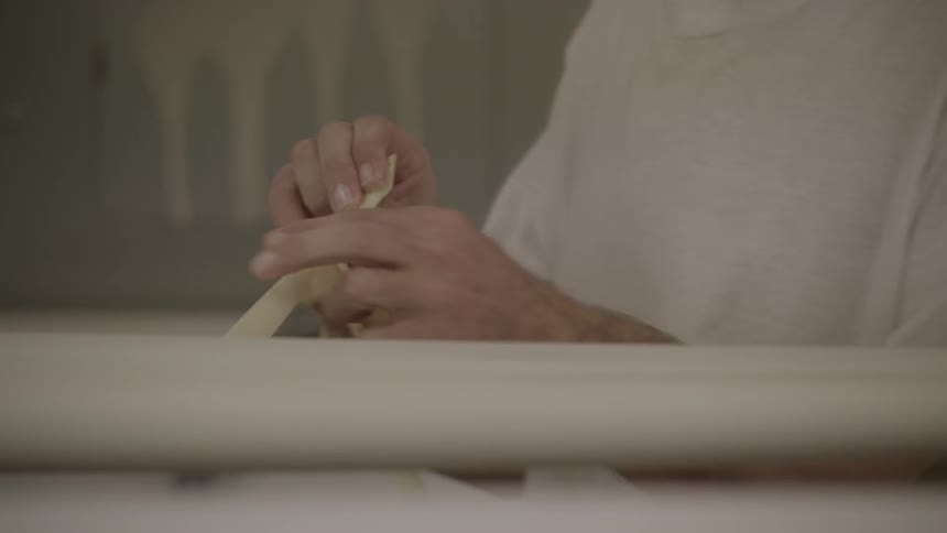 A person pulls tape off of a board