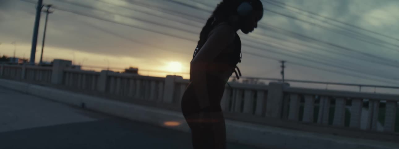 Woman with headphones doing stretching outdoors at sunrise