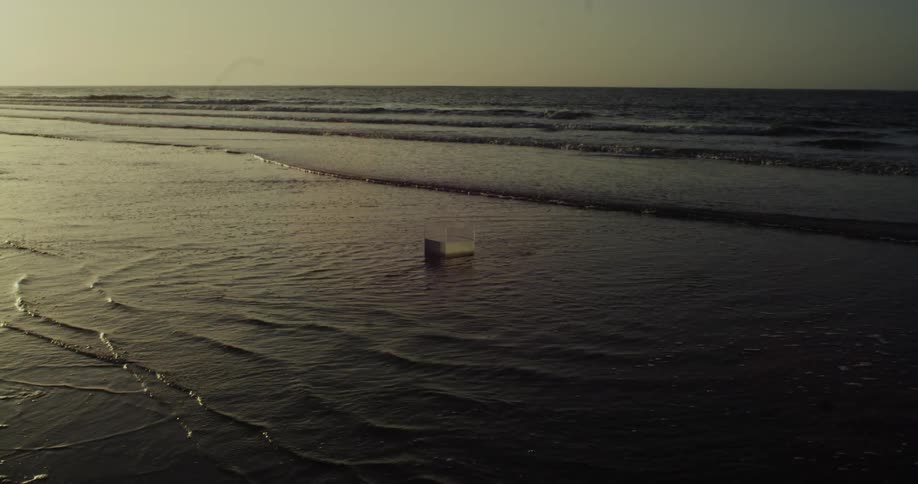 Transparent box with water floating on the beach