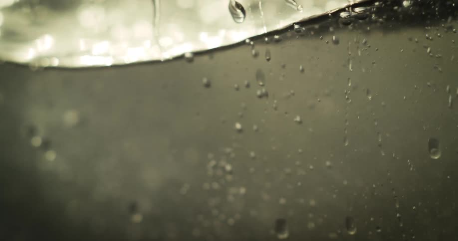 Sloshing water leaves bubbles and droplets on a glass panel during the daytime