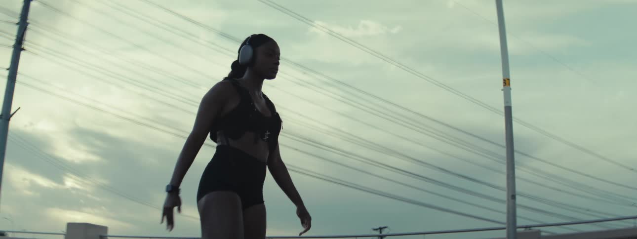 A lady stretches her legs while standing outdoor in the morning with headset on