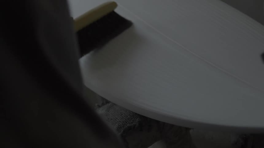 A person is working shaving a surfboard