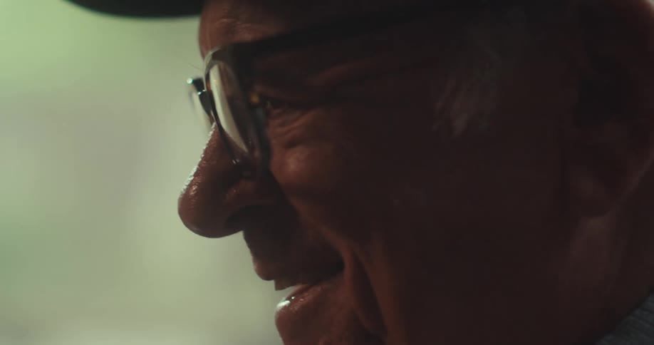 An elderly man wearing a hat and glasses is indoors talking on a video call