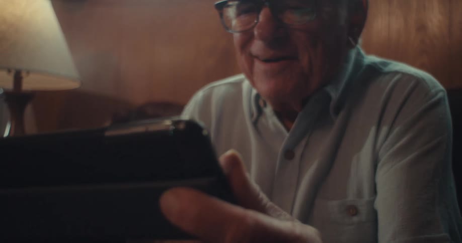 A man smiles while viewing his tablet