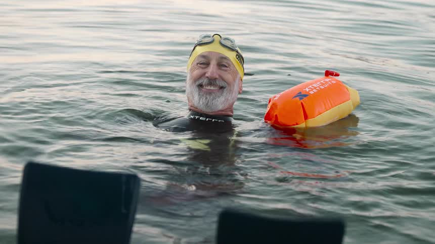 Older man smiles while floating on his back with a flotation device