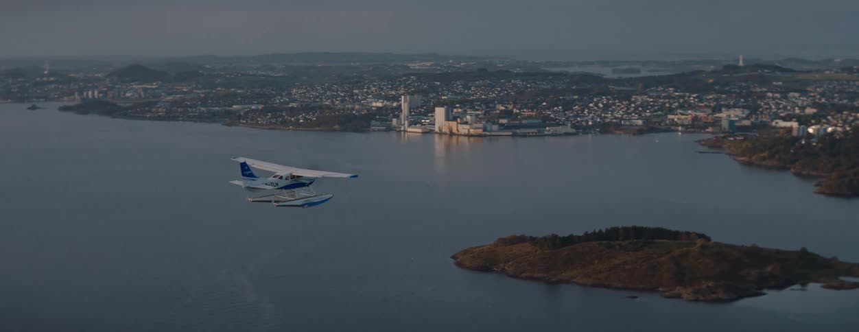 Single engine plane crossing the sea with a city in the background