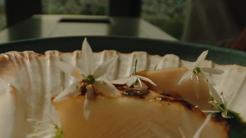 Conch shell plate rotating displaying a seafood cuisine adorned with flowers