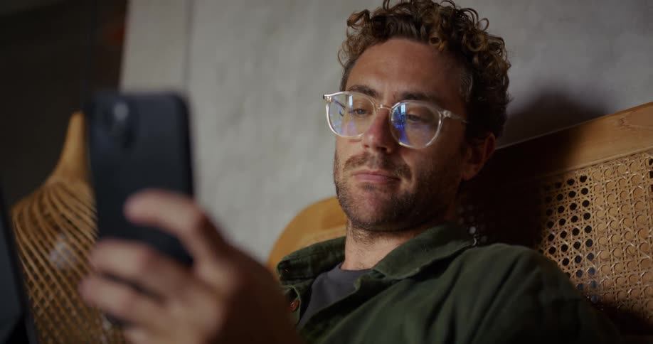Man with glasses typing on a smartphone