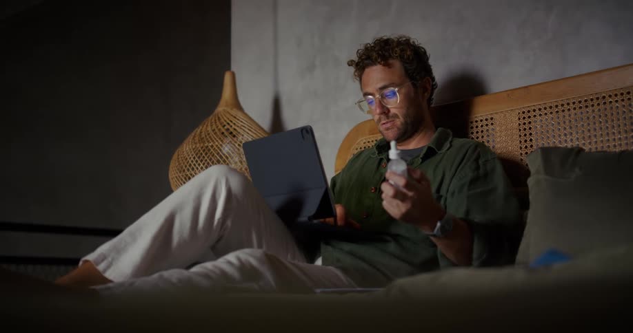 Man sitting on bed interacting with a tablet