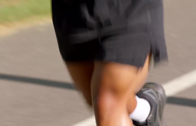 A black man jogs along a street in daytime