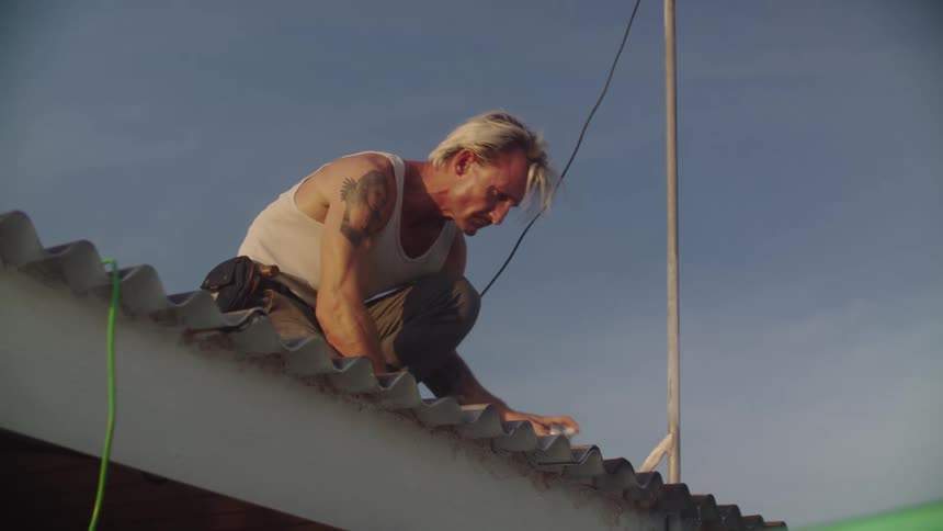 Man on a roof applying spray paint