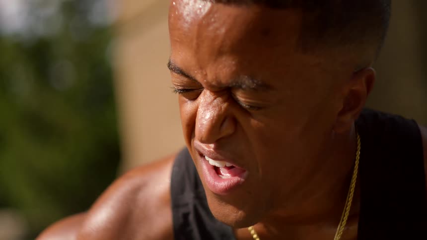 Man taking deep breaths with tired expression and sweaty face