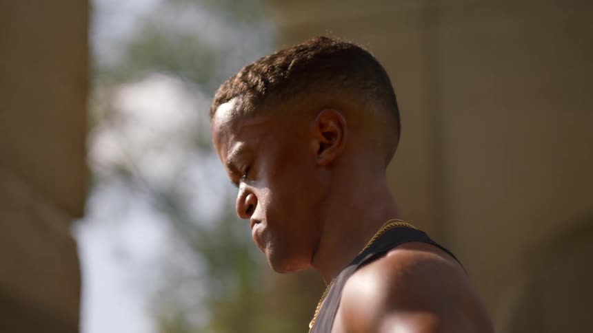 Man in tank top outdoors with focused expression