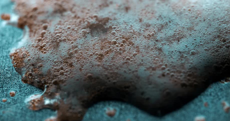 Brown foam or mold like substance forming and bubbling on a surface captured in a highly magnified textured closeup