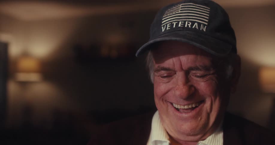 An elderly man typing on a laptop and laughing