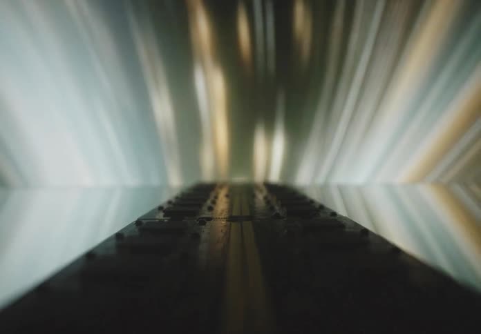 A pair of ram memory sticks rest on a reflective surface illuminated by surrounding dynamic streaking light effects