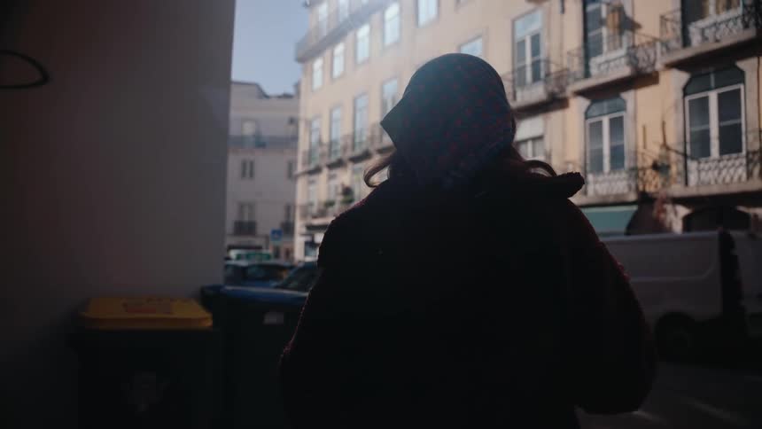 A woman in a neighborhood smoking a cigarette and exhaling smoke