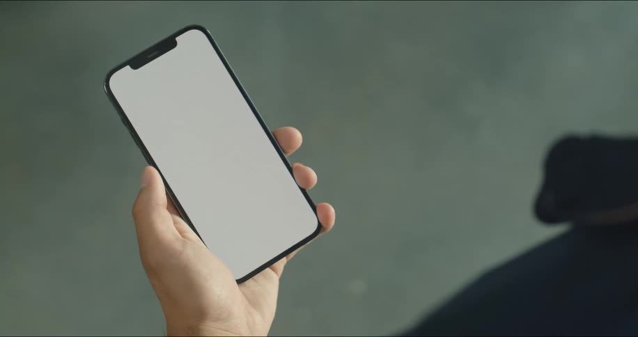 Person holds a smartphone in one hand while using a thumb to scroll