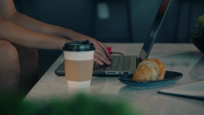 A woman is sitting and typing on a laptop