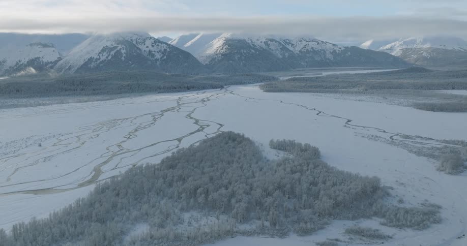 Aerial view of a frozen river surrounded by snowy mountains