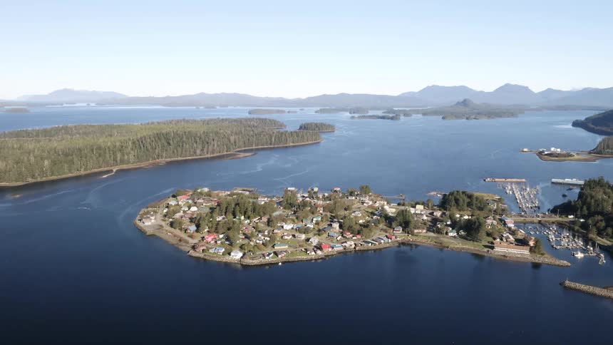 Aerial view of a small coastal town on an island surrounded by calm blue waters and forested landmasses