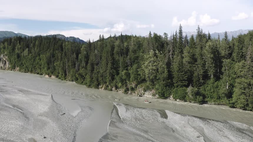 A wide silty river flows through a forested valley