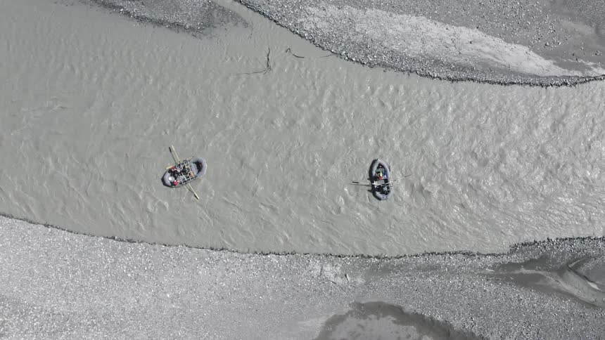 Two groups of people are river rafting on a sunny day