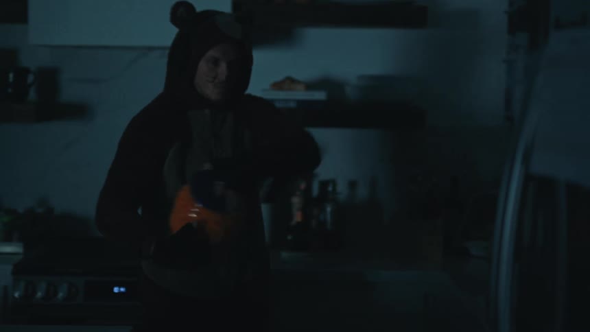 Man in costume opening refrigerator door in kitchen at night