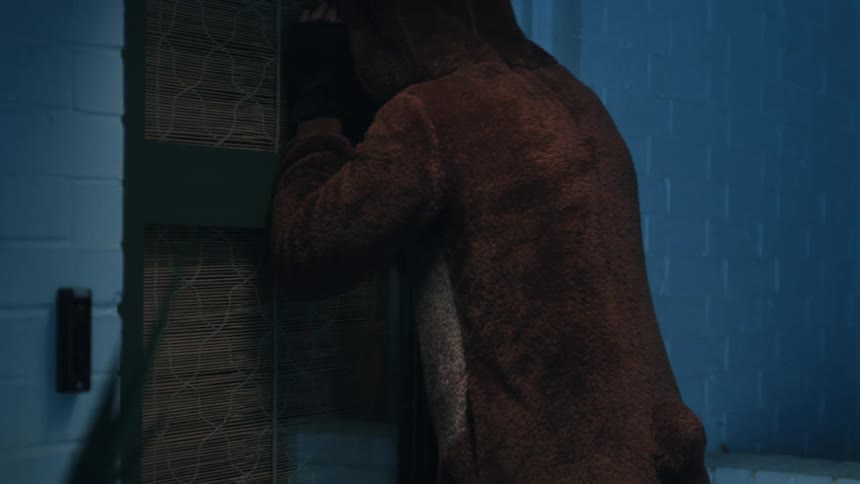 Person in brown overalls trying to enter the door of a house