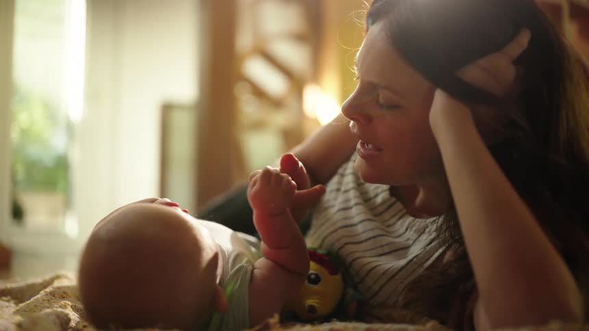 Mother lying down playing with her baby