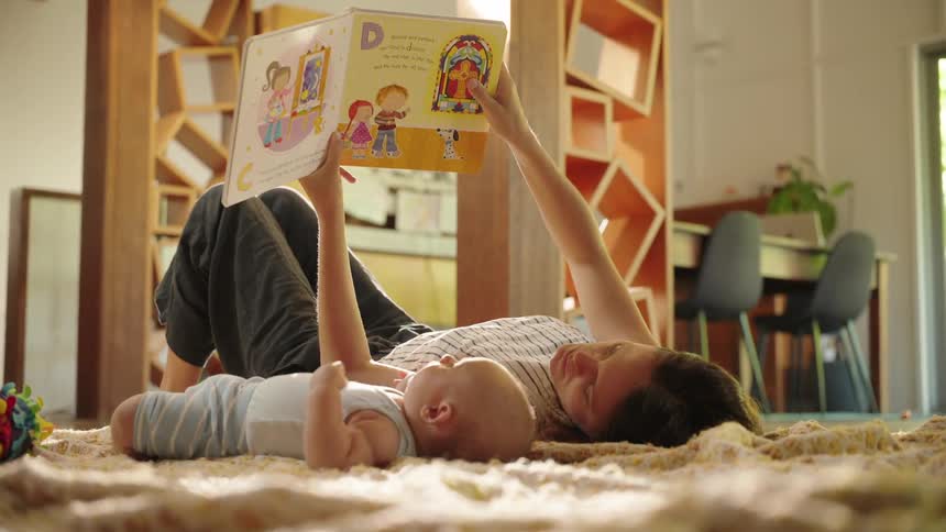 A mother is reading a book to her baby