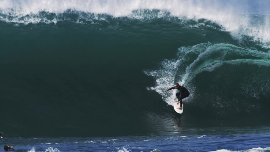 A man surfs an ocean wave at midday