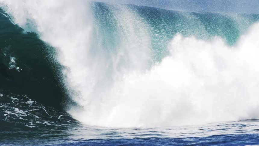 A powerful churning wave explodes outwards in a burst of white foam and blue water