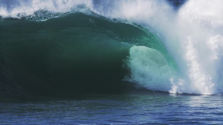 The wave slowly rises and crashes into the ocean