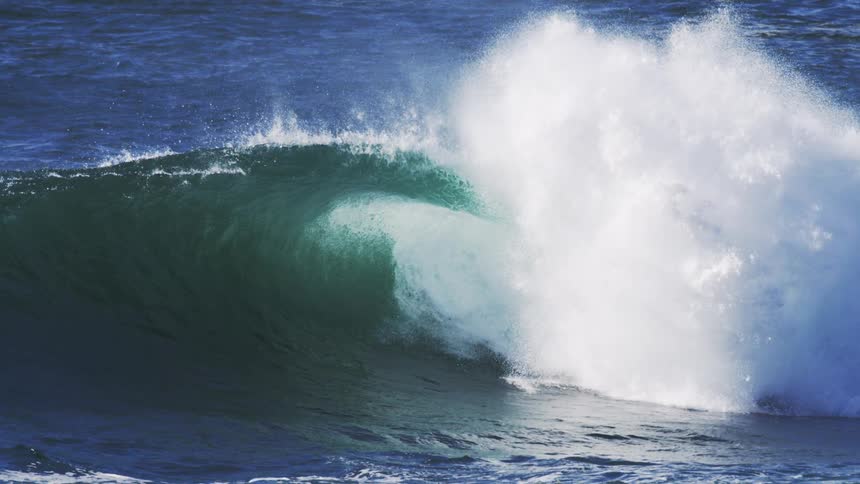 A powerful ocean wave crashing sending spray high into the air with a dark blue and teal color palette