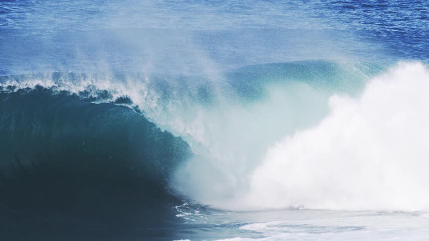Large wave crashing at the beach on a sunny day
