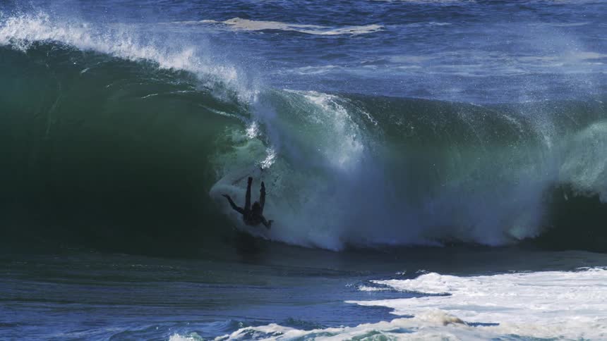 A man falling off his surfboard while riding the barrel of a wave
