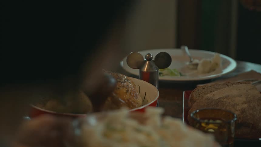 A man and a woman are sitting at the dinner table eating roast chicken