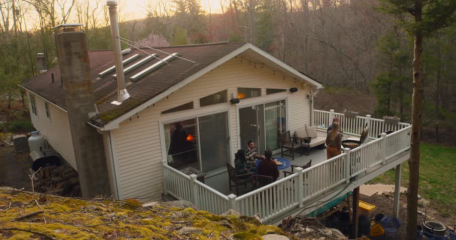 Aerial of friends gathered on large deck on a house in the wilderness for a bbq