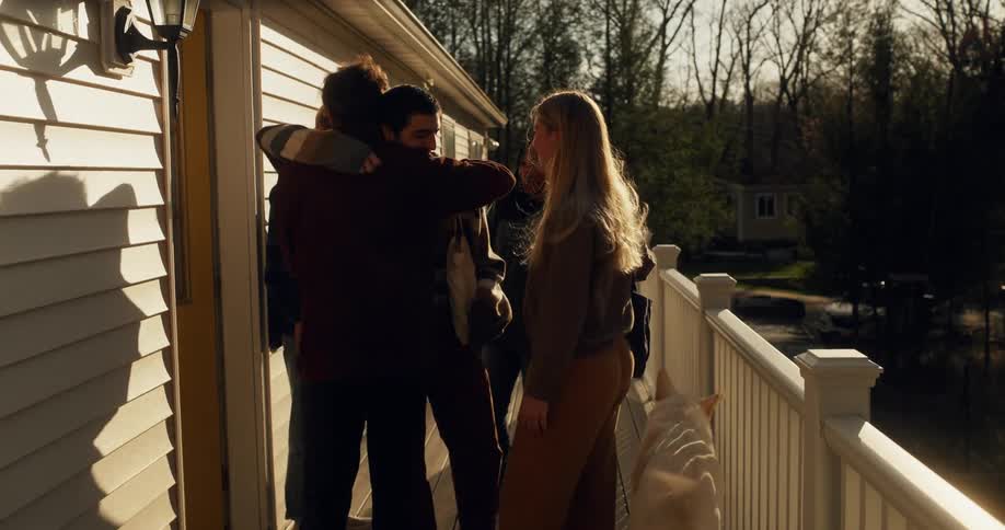 Friends in an outside hallway of a house greeting each other