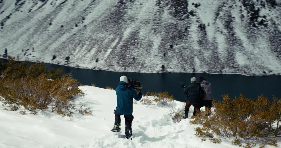 A person films a couple people near a cliff