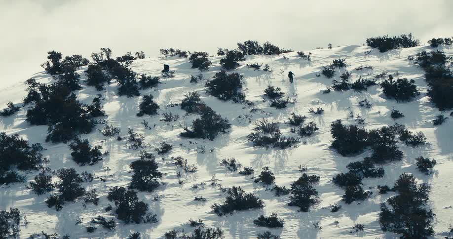 Two people climbing a steep snowy mountain
