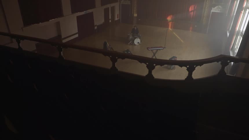 Man in an empty hall playing drums