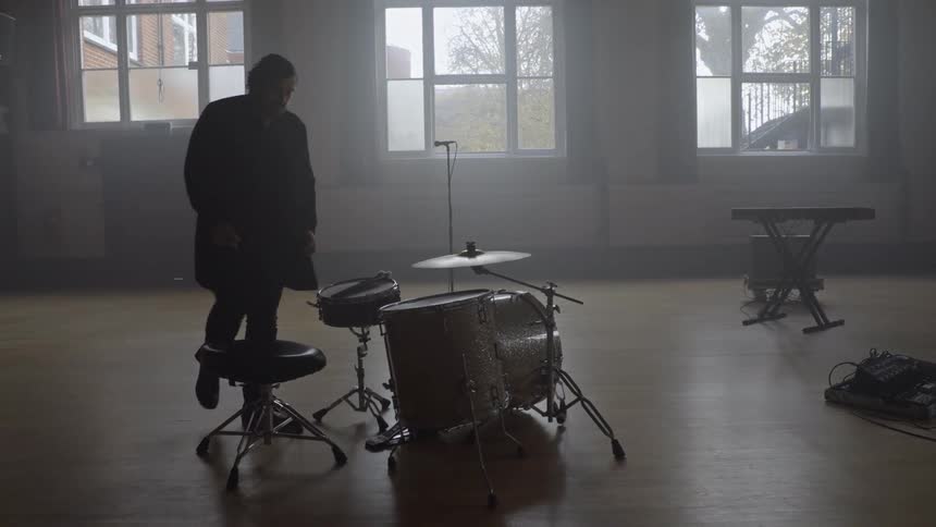 Man walking and sitting on chair in front of musical drums