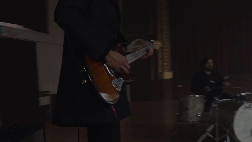 Man in a hall playing guitar in a band