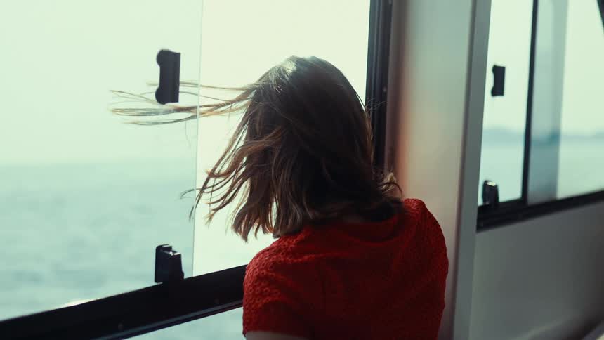 Woman watching the sea from the window of a moving boat