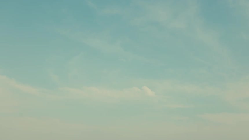 Two seagulls fly across a light blue sky with wispy clouds before the view tilts fully upwards to the expansive sky