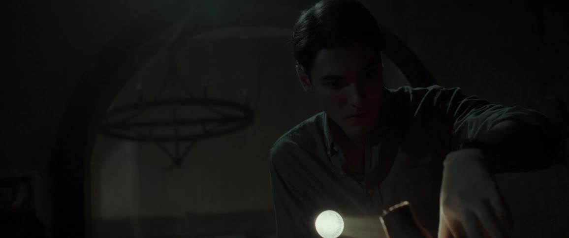 A man cautiously enters a dark eerie room with a flashlight appearing tense as he investigates his surroundings