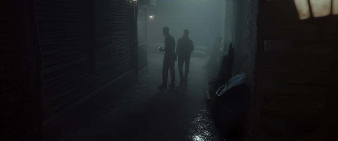 Two shadowy figures move cautiously through a narrow dimly lit alley at night surrounded by fog and scattered debris creating a tense and mysterious atmosphere