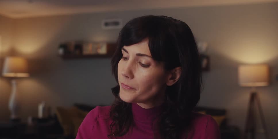 Woman sitting at home puts on her glasses briefly to take care of a task before stretching